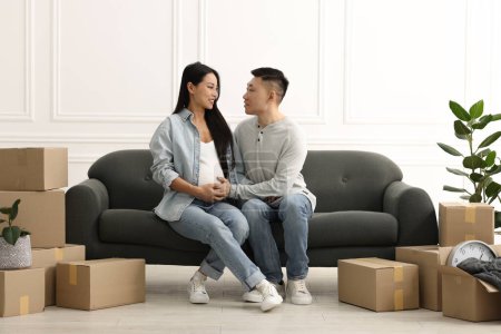 Foto de Mujer embarazada y su marido en el sofá en su nuevo apartamento - Imagen libre de derechos