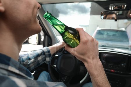 Téléchargez les photos : Homme avec une bouteille de bière voiture de conduite, gros plan. Ne pas boire et conduire concept - en image libre de droit