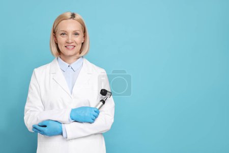 Téléchargez les photos : Happy dermatologist with dermatoscope on light blue background, space for text - en image libre de droit