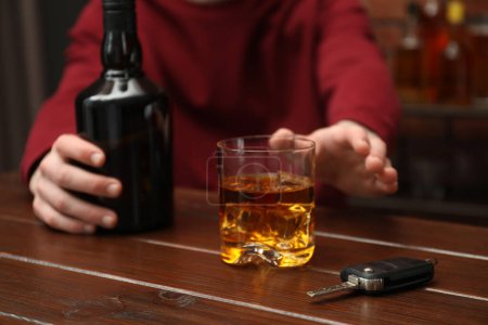 Téléchargez les photos : Un homme cherchant une boisson alcoolisée à table avec des clés de voiture, gros plan. Ne pas boire et conduire concept - en image libre de droit
