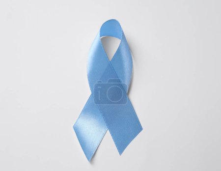 Internationaler Tag der Schuppenflechte. Hellblaues Band als Symbol der Unterstützung auf weißem Hintergrund, Ansicht von oben