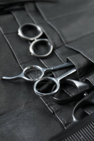 Hairdresser tools. Professional scissors and comb in leather organizer, closeup