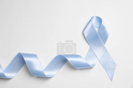 Internationaler Tag der Schuppenflechte. Hellblaues Band als Symbol der Unterstützung auf weißem Hintergrund, Ansicht von oben