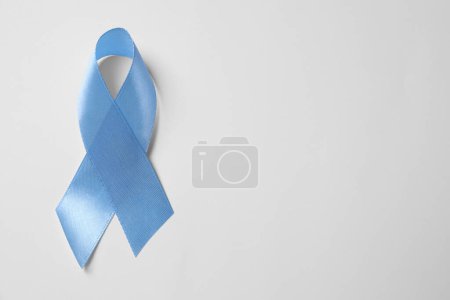Internationaler Tag der Schuppenflechte. Hellblaues Band als Symbol der Unterstützung auf weißem Hintergrund, Draufsicht. Raum für Text