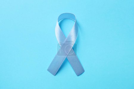 Día Internacional de la Psoriasis. Cinta como símbolo de apoyo sobre fondo azul claro, vista superior