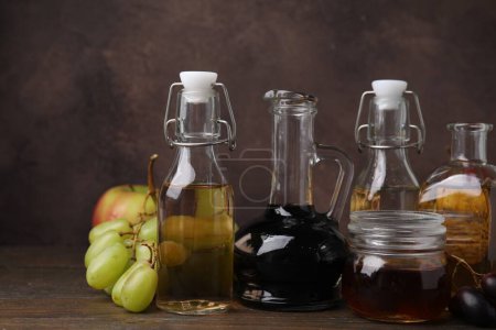 Different types of vinegar and fresh fruits on wooden table