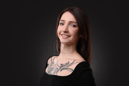 Retrato de mujer tatuada sonriente sobre fondo negro
