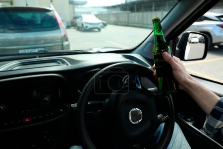Mann mit Bierflasche am Steuer, Nahaufnahme. Nicht trinken und Auto fahren