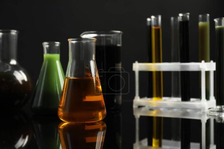 Laborgläser mit verschiedenen Ölsorten auf schwarzem Hintergrund