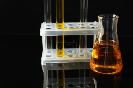 Téléchargez les photos : Verrerie de laboratoire avec différents types d'huile sur fond noir - en image libre de droit