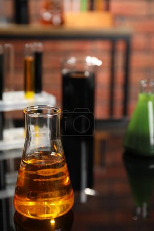 Téléchargez les photos : Laboratory glassware with different types of oil on black mirror table, closeup - en image libre de droit