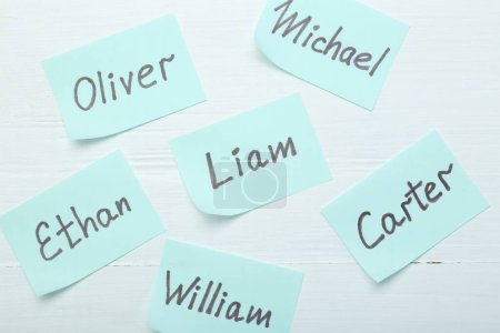 Autocollants en papier avec des noms différents sur fond blanc en bois, pose plate. Choisir le nom du bébé