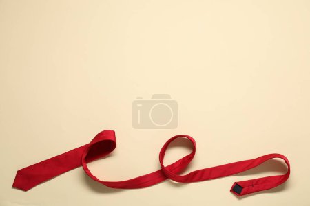 Corbata roja sobre fondo beige, vista superior. Espacio para texto