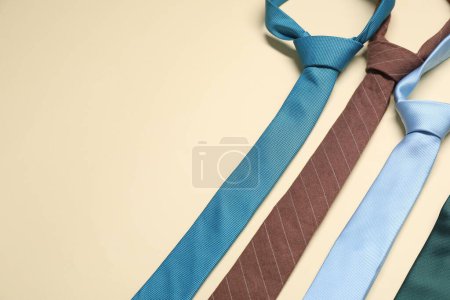 Different neckties on beige background, above view. Space for text