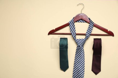 Hanger and neckties on beige background, flat lay. Space for text