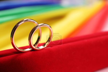 Wedding rings on rainbow LGBT flag, closeup