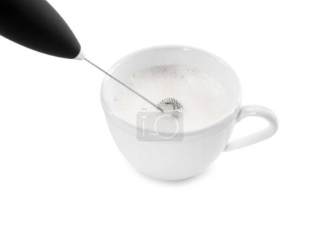 Batiendo la leche en taza con la mini batidora (varita de espuma) aislada en blanco