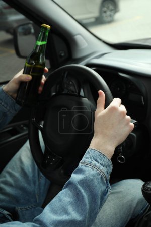 Mann mit Bierflasche am Steuer, Nahaufnahme. Nicht trinken und Auto fahren