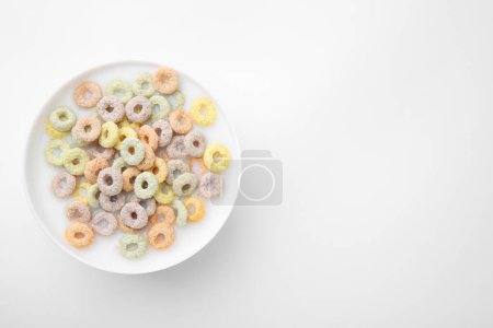 Photo for Tasty colorful cereal rings and milk in bowl on white background, top view. Space for text - Royalty Free Image