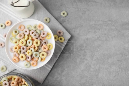 Photo for Tasty colorful cereal rings and milk in bowl on grey table, flat lay. Space for text - Royalty Free Image