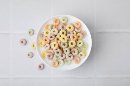Photo for Cereal rings and milk in bowl on white tiled table, top view - Royalty Free Image