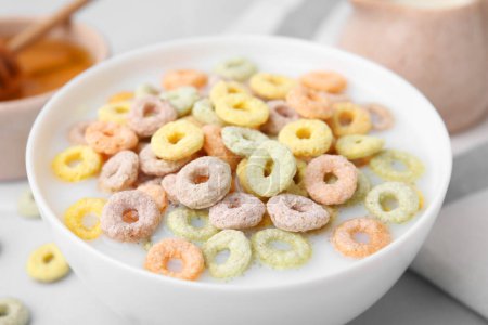 Photo for Cereal rings and milk in bowl on white table, closeup - Royalty Free Image