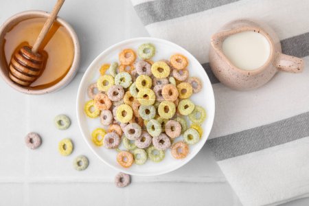 Photo for Cereal rings and milk in bowl on white tiled table, flat lay - Royalty Free Image