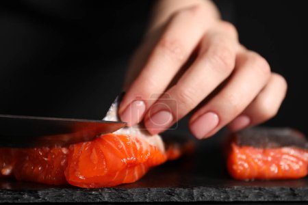 Téléchargez les photos : Chef enlevant les écailles du saumon pour les sushis à table noire, gros plan - en image libre de droit