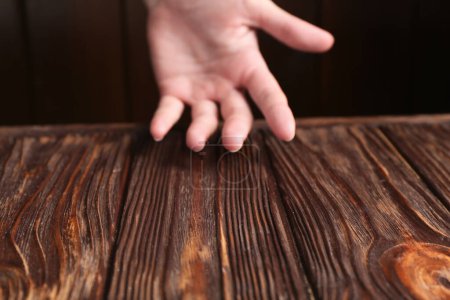 Woman holding hand above wooden table, selective focus. Space for text
