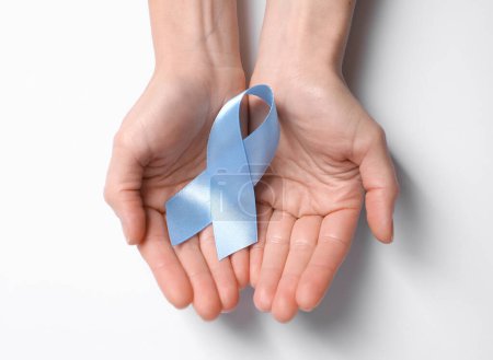 International Psoriasis Day. Woman with light blue ribbon as symbol of support on white background, top view