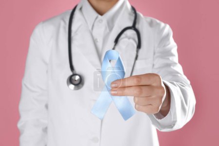 International Psoriasis Day. Doctor with light blue ribbon as symbol of support on pink background, closeup