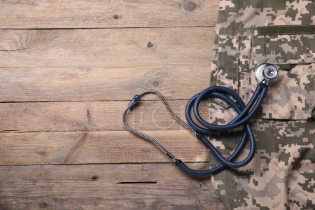 Photo for Stethoscope and military uniform on wooden background, flat lay. Space for text - Royalty Free Image
