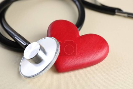 Foto de Estetoscopio y corazón rojo sobre fondo beige, primer plano - Imagen libre de derechos