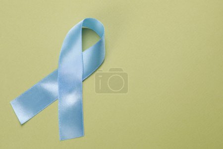 Día Internacional de la Psoriasis. Cinta como símbolo de apoyo sobre fondo verde, vista superior. Espacio para texto