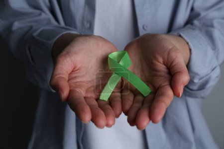 Woman with green awareness ribbon, closeup view