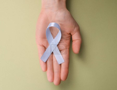 International Psoriasis Day. Woman with light blue ribbon as symbol of support on green background, top view. Space for text