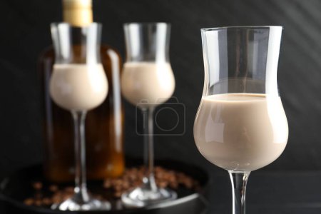 Téléchargez les photos : Crème de café liqueur dans des verres, bouteille et haricots sur la table, gros plan - en image libre de droit