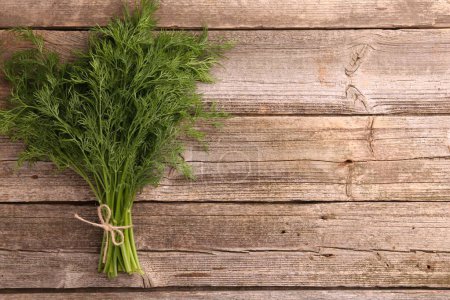 Bunch of fresh dill on wooden table, top view. Space for text