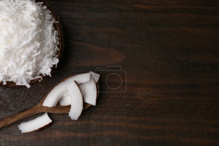 Coconut flakes, spoon and nut on wooden table, top view. Space for text