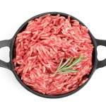 Raw ground meat and rosemary in bowl isolated on white, top view