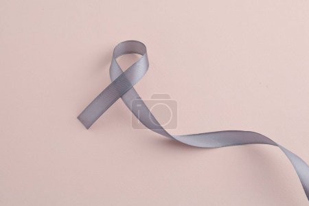 Photo for Grey awareness ribbon on beige background, top view - Royalty Free Image