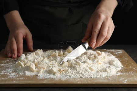 Woman making shortcrust pastry with knife at table, closeup