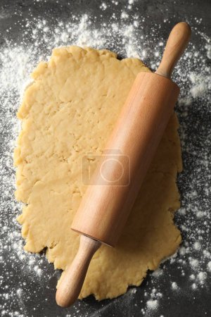 Making shortcrust pastry. Raw dough, flour and rolling pin on grey table, top view