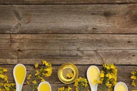 Rapsöl in Schale, Sauciere und schöne gelbe Blumen auf Holztisch, flach gelegt. Raum für Text
