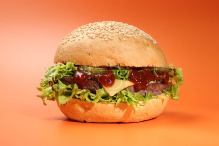 Delicious cheeseburger with lettuce, pickle, ketchup and patty on coral background, closeup