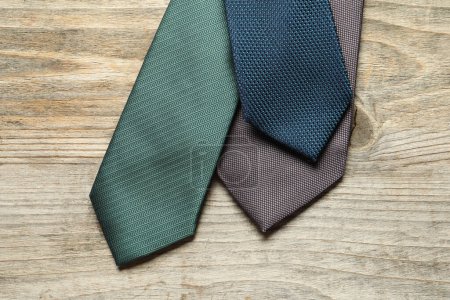 Different neckties on light wooden table, flat lay
