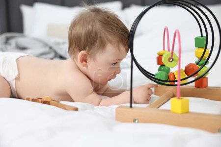 Cute baby boy with toys on bed at home