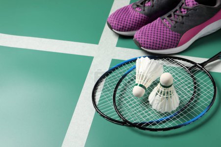 Photo for Feather badminton shuttlecocks, rackets and sneakers on court, space for text - Royalty Free Image