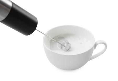 Batiendo la leche en taza con mini mezclador (varita de espuma) aislado en blanco, primer plano