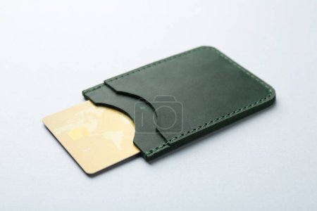 Frau mit Lederkartenetui mit Kreditkarte auf hellgrauem Hintergrund